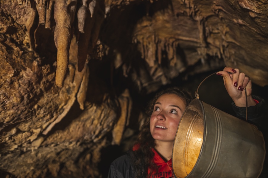 Young woman holding lantern on haunted lantern tour in a cave