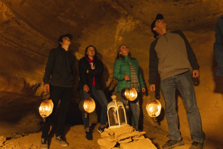 4 people admiring the beauty of the cave during haunted lantern tour