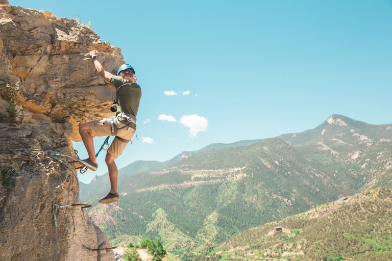 Man climbing cliff during via ferrata experience in Colorado Springs.